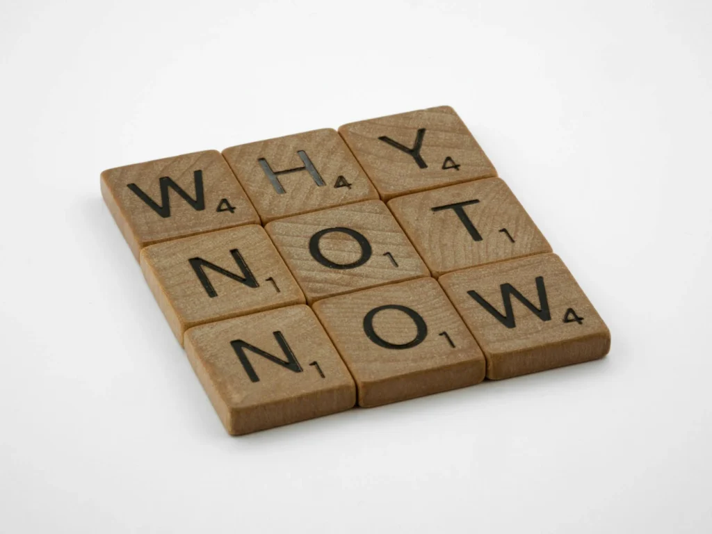 scabble pieces spelling out 'why not now'.
